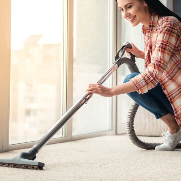 Smiling lady cleaning rug | Kelly's Carpet & Furniture